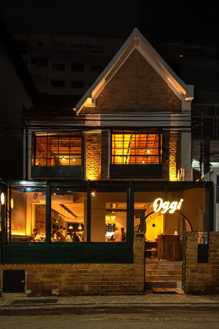 Fachada iluminada do casarão da Oggi Botafogo à noite