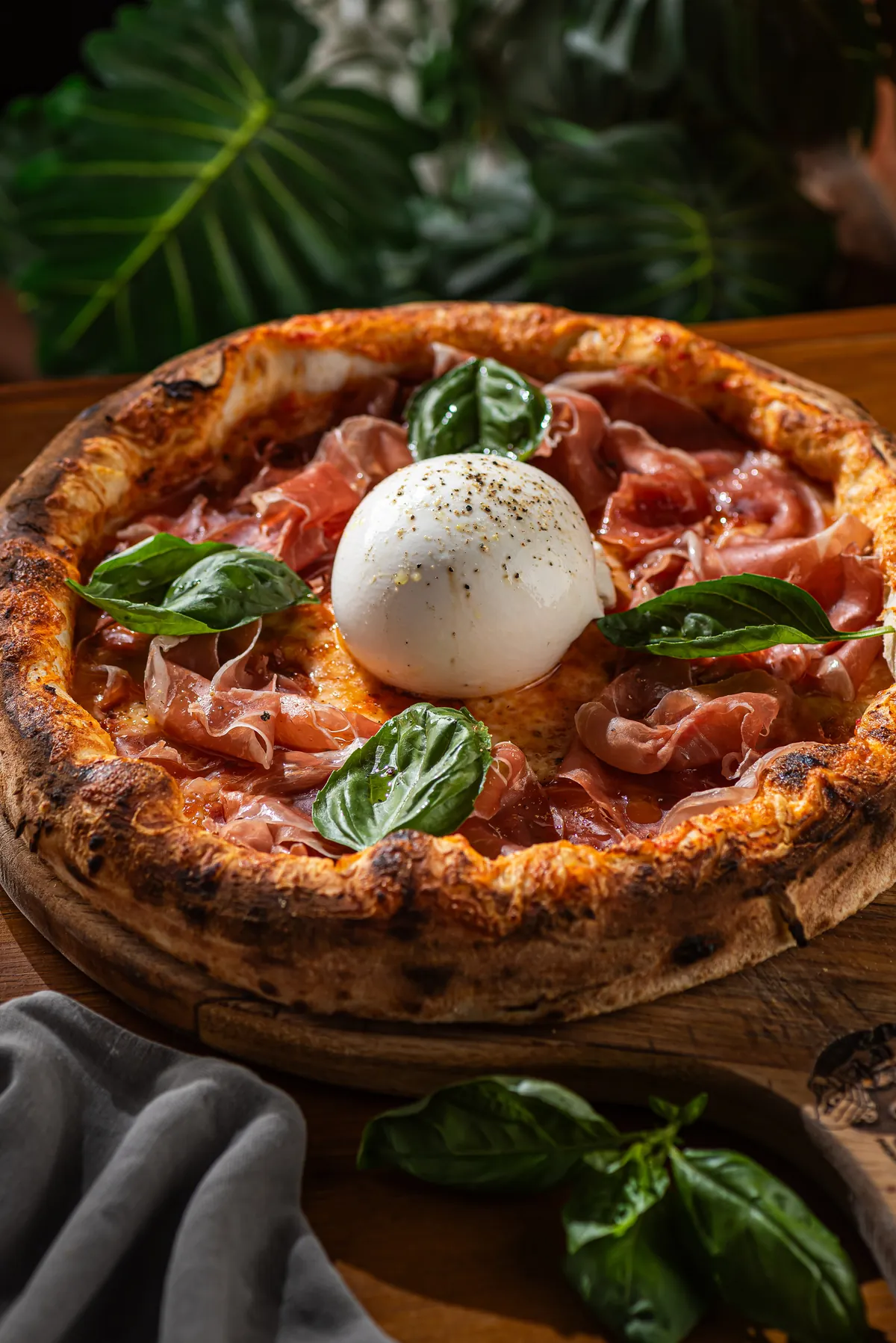Pizza napoletana com burrata inteira, presunto de Parma e manjericão fresco, de bordas altas e tostadas